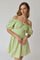 woman wearing a light green off-the-shoulder dress with puff sleeves and a lace-up detail