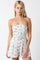 woman wearing a strapless floral romper with a belted waist