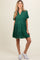 woman wearing a green short sleeve maternity dress with tiered detailing and frayed hem