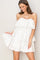 woman wearing a white tiered strapless dress with ruffle details and a flowy silhouette