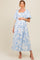 woman wearing a blue floral print maternity dress with puff sleeves and a visible baby bump
