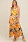 woman wearing a sleeveless yellow and orange patterned maternity maxi dress with a flowy skirt and adjustable shoulder ties, baby bump visible