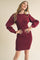 woman wearing a burgundy ribbed bodycon dress with long puff sleeves and a crew neckline