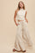 woman wearing a cream sleeveless crop top and wide-leg tiered pants with pockets