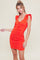 woman wearing a bright orange short ruched dress with puff sleeves and a front tie detail