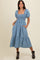 woman wearing a light blue puff sleeve denim midi dress with a smocked bodice and pockets