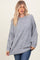 woman wearing a gray oversized sweater with dropped shoulders and a relaxed fit, paired with blue jeans