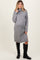 woman wearing a grey turtleneck maternity sweater dress with side slits and knee-high black boots, showcasing her baby bump