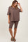 woman wearing a brown oversized t-shirt with a pocket and matching bike shorts, styled with casual sandals