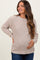 woman wearing a beige knit maternity sweater and holding her baby bump