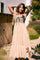 woman wearing a beige tiered sundress with a black lace-up detail and a fitted bodice, posed outdoors among greenery