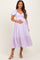 woman wearing a lavender striped maternity dress with a puff sleeve and holding her baby bump