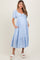 woman wearing a light blue striped maternity dress with puff sleeves and pockets, showcasing her baby bump