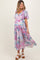 woman wearing a pastel floral print maternity dress with flutter sleeves and a flowy skirt, highlighting her baby bump
