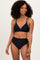 woman wearing a black bikini with decorative white pom-poms and high-waisted bottoms
