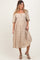 woman wearing a beige maternity dress with floral designs and puff sleeves, standing with a relaxed pose