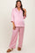 woman wearing a light pink satin maternity pajama set with a button-up top and loose-fitting pants, showing her baby bump
