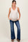 woman wearing a nude maternity tank top and flared jeans, showing her baby bump with hands in pockets