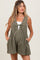 woman wearing an olive green maternity romper with pleats and front tie detail, featuring side pockets