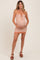 woman wearing a rust and cream checkered maternity dress with a tie front, cradling her baby bump