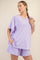woman wearing a lavender oversized t-shirt and matching shorts, styled casually with a braid in her hair
