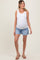 woman wearing a white ribbed maternity tank top and denim shorts, showing her baby bump