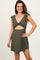 woman wearing an olive green ruffled short dress with a cut-out design and twist front detail