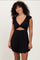 woman wearing a black ruffled mini dress with a twisted front and open back