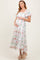 woman wearing a floral maternity maxi dress with a square neckline and puff sleeves, holding her baby bump