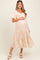 woman wearing a beige lace embroidered maternity dress with short sleeves and a tiered hem, holding her baby bump