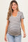 woman wearing a beige and black striped maternity top with a scoop neckline and visible baby bump