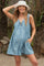 woman wearing a light blue floral maternity dress with a tie front and pockets, smiling and showing her baby bump