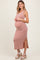 woman wearing a light pink ribbed maternity maxi dress with a side slit and cradling her baby bump