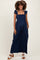 woman wearing a navy blue maternity jumpsuit with ruffled straps and a smocked bodice, holding hands in pockets