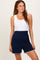 woman wearing a white ribbed tank top and navy blue shorts with a high waistband and scalloped hem