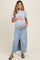 woman wearing a gray short sleeve maternity top and a light blue denim maxi skirt, holding her baby bump
