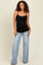 woman wearing a black maternity tank top and light wash wide-leg jeans with a visible baby bump