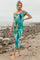 woman wearing a turquoise and green tie-dye off-shoulder maternity dress with a visible baby bump on the beach