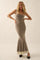 woman wearing a taupe one-shoulder mermaid maxi dress with a ruffled hem and a side bow detail