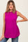 woman wearing a bright fuchsia maternity top with a flowy silhouette and sleeveless design, posing with one hand on her hip