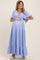 woman wearing a light blue maternity maxi dress with a tie-front and flutter sleeves, holding her baby bump