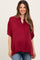 woman wearing a burgundy button-up maternity top with short sleeves and a visible baby bump