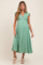 woman wearing a sage green maternity maxi dress with polka dots, a v-neckline, and tie straps, showcasing her baby bump