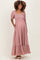 woman wearing a pink floral maternity maxi dress with puff sleeves and pockets, displaying her baby bump