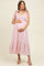 woman wearing a pink floral maternity dress with smocked bodice and tie straps, showcasing her baby bump