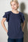 woman wearing a navy blue short sleeve top with ruffled sleeves and a relaxed fit