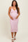 woman wearing a light pink knitted maternity dress with a ruffled neckline and a visible baby bump