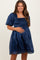 woman wearing a navy blue short sleeve smocked maternity dress and holding her baby bump