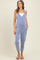 woman wearing a blue and white striped maternity jumpsuit with pockets over a white tank top