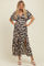 woman wearing a leopard print maternity maxi dress with short sleeves and a thigh-high slit, showing her baby bump